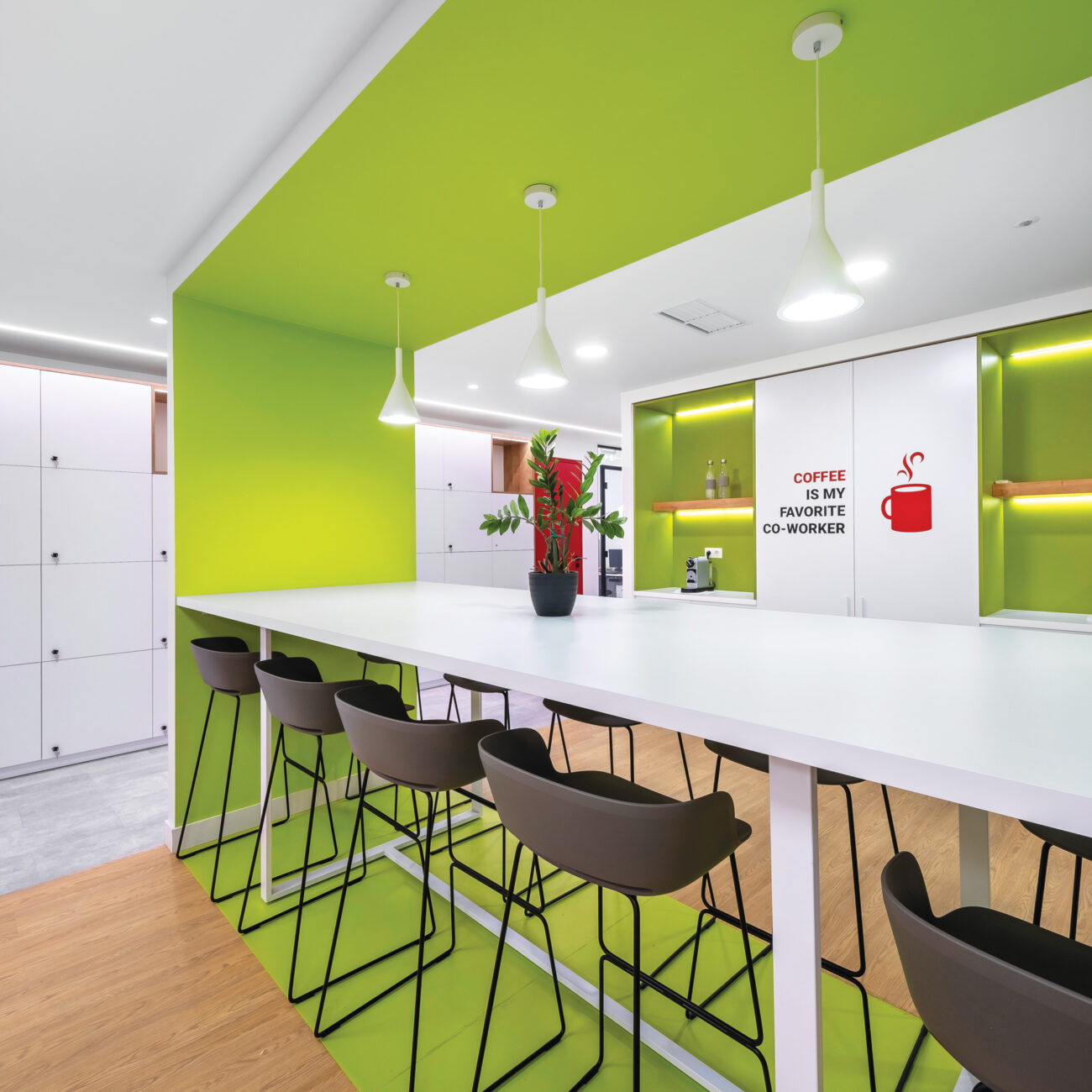 Merck Group workplace project by STIRIXIS Group showing canteen area with white bar counter, high stools and bright open dining space