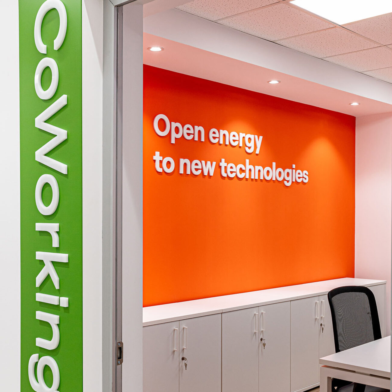 E-Distributie by Enel workplace project by STIRIXIS Group showing coworking area with open energy to new technologies orange brand wall