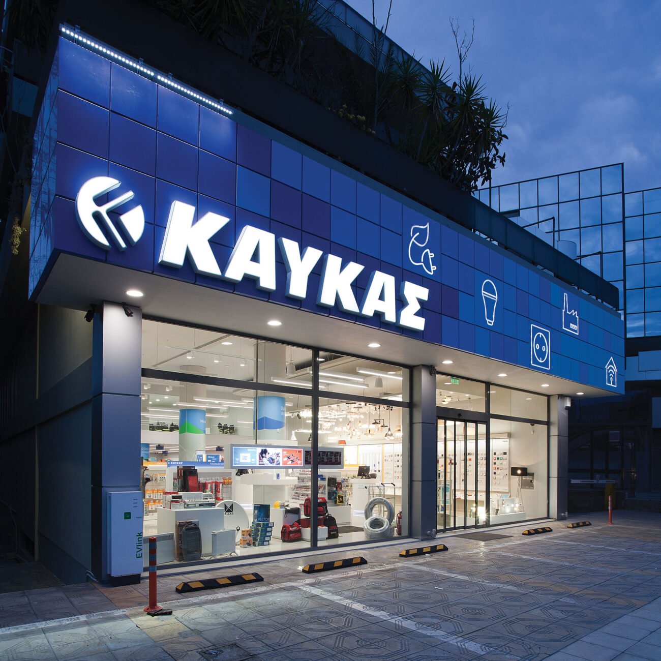 Kafkas retail project by STIRIXIS Group showing exterior store facade at night with illuminated blue Kafkas signage and glazed shopfront