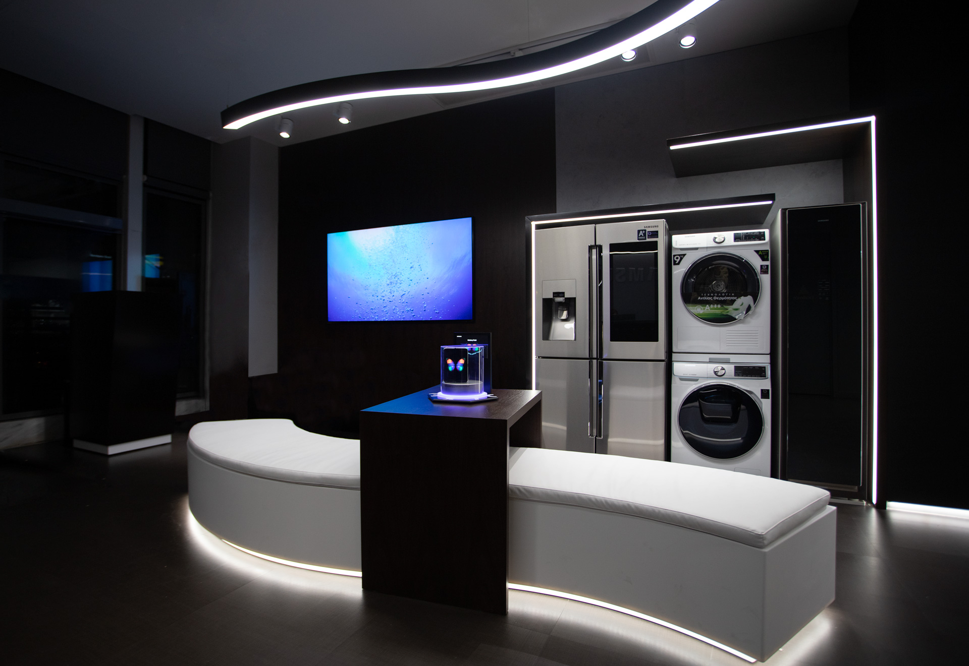 Samsung showroom retail project by STIRIXIS Group showing product display area with home appliances and dramatic dark interior lighting
