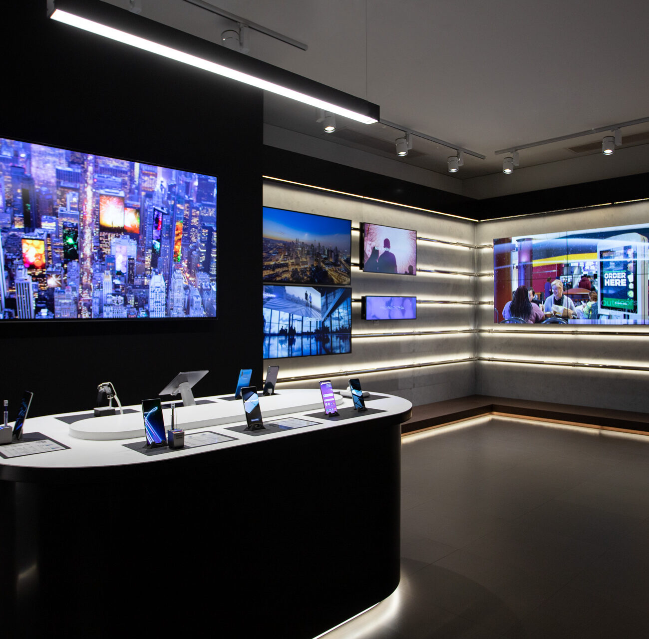 Samsung showroom retail project by STIRIXIS Group showing multi-screen display zone with product categories and dark premium interior