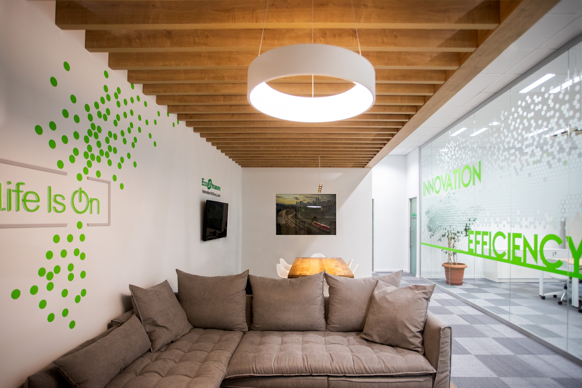 Schneider Electric headquarters workplace project by STIRIXIS Group showing lounge area with Life Is On and efficiency brand wall and relaxed sofa seating