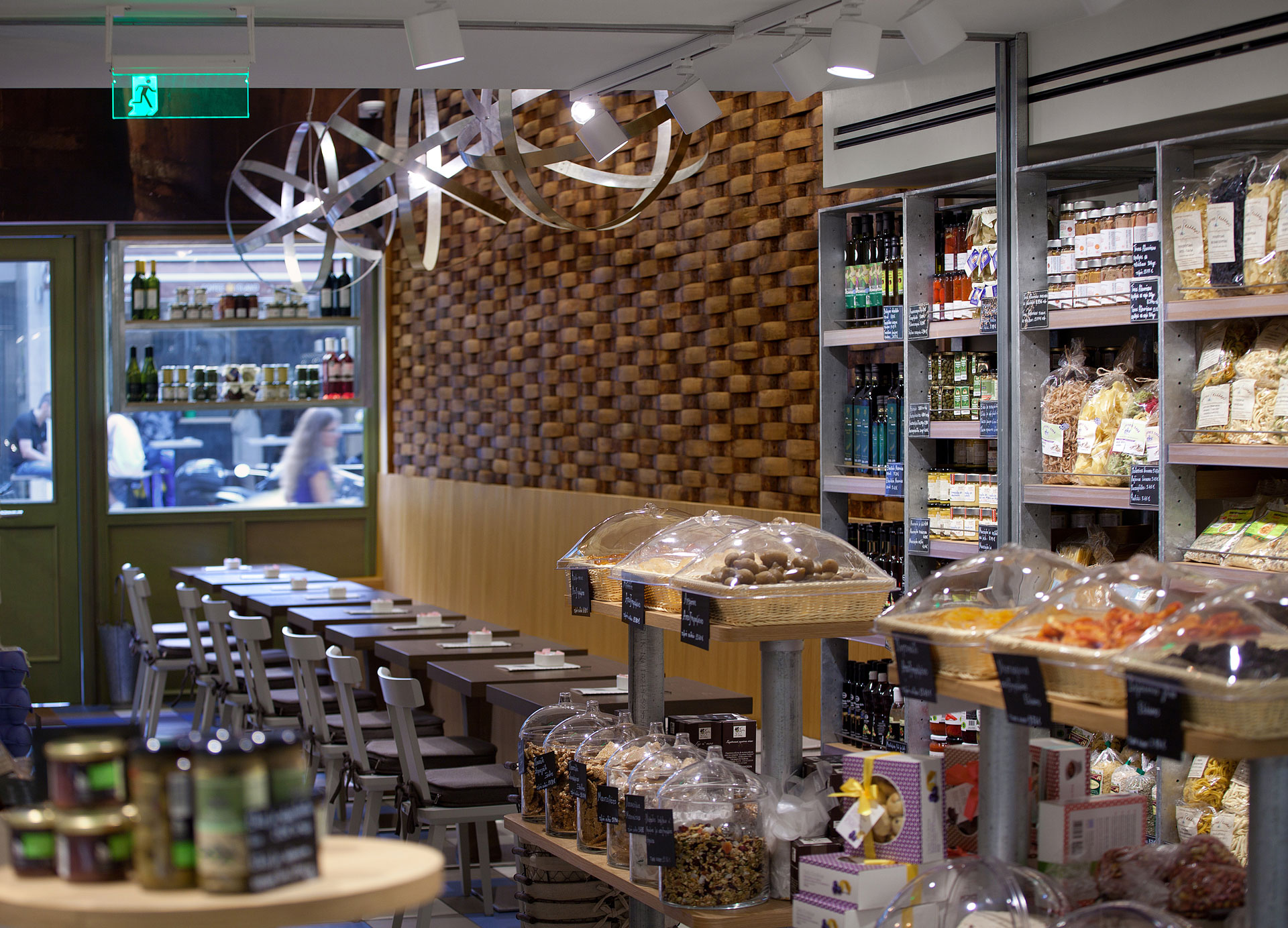 Kostarelos Deli hospitality project by STIRIXIS Group showing customer seating area alongside product shelving with warm wood finishes