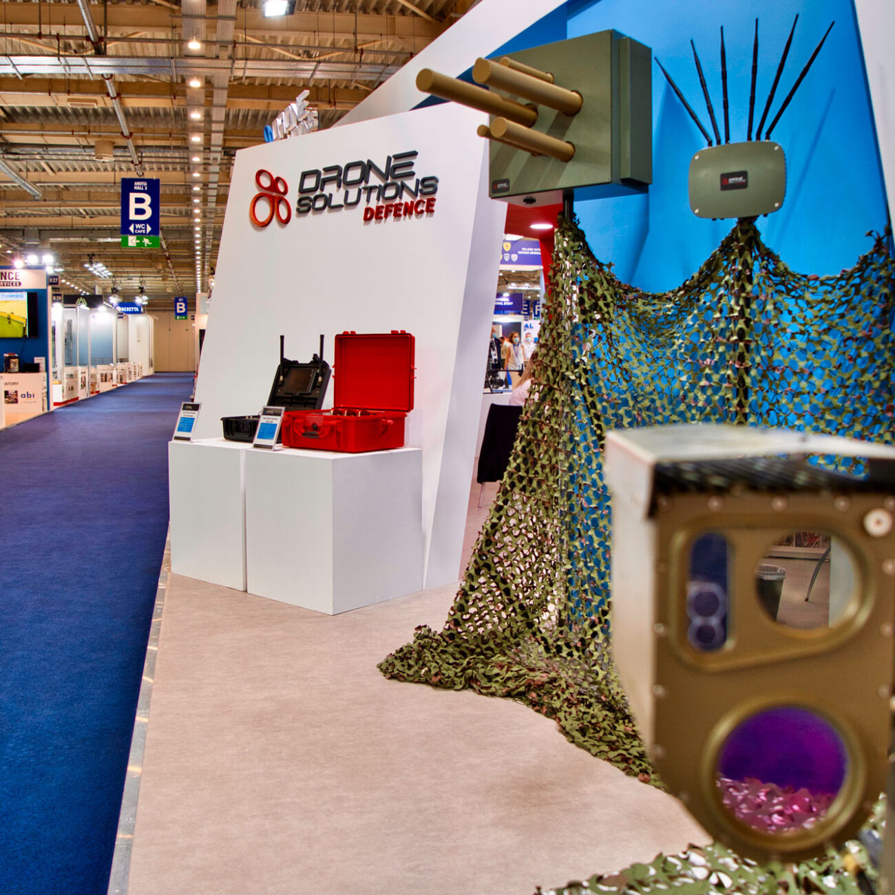 Drone Solutions exhibition stand by STIRIXIS Group showing stand with camouflage net installation and branded product display