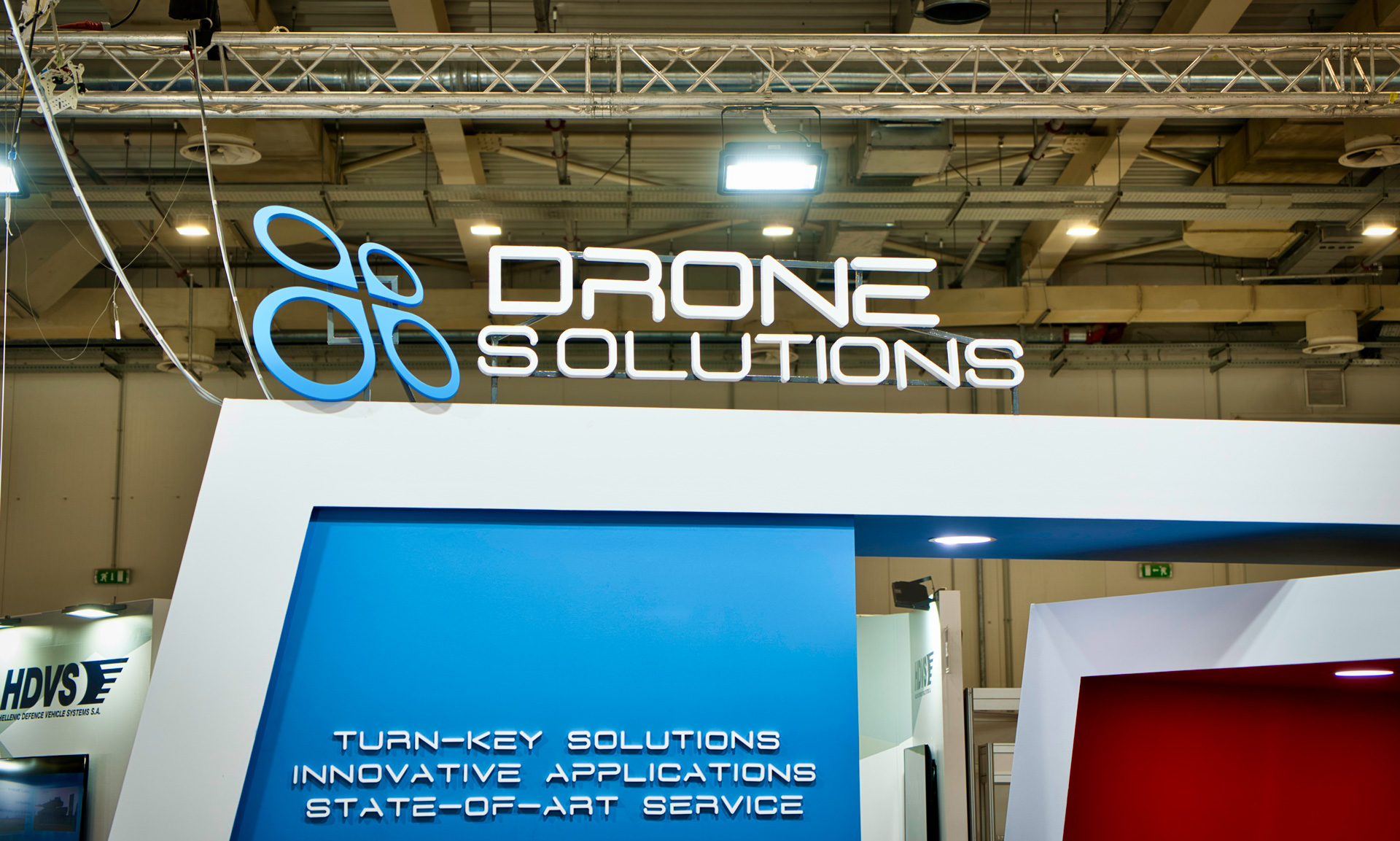 Drone Solutions exhibition stand by STIRIXIS Group showing stand facade with Drone Solutions turn-key solutions branded signage and blue identity