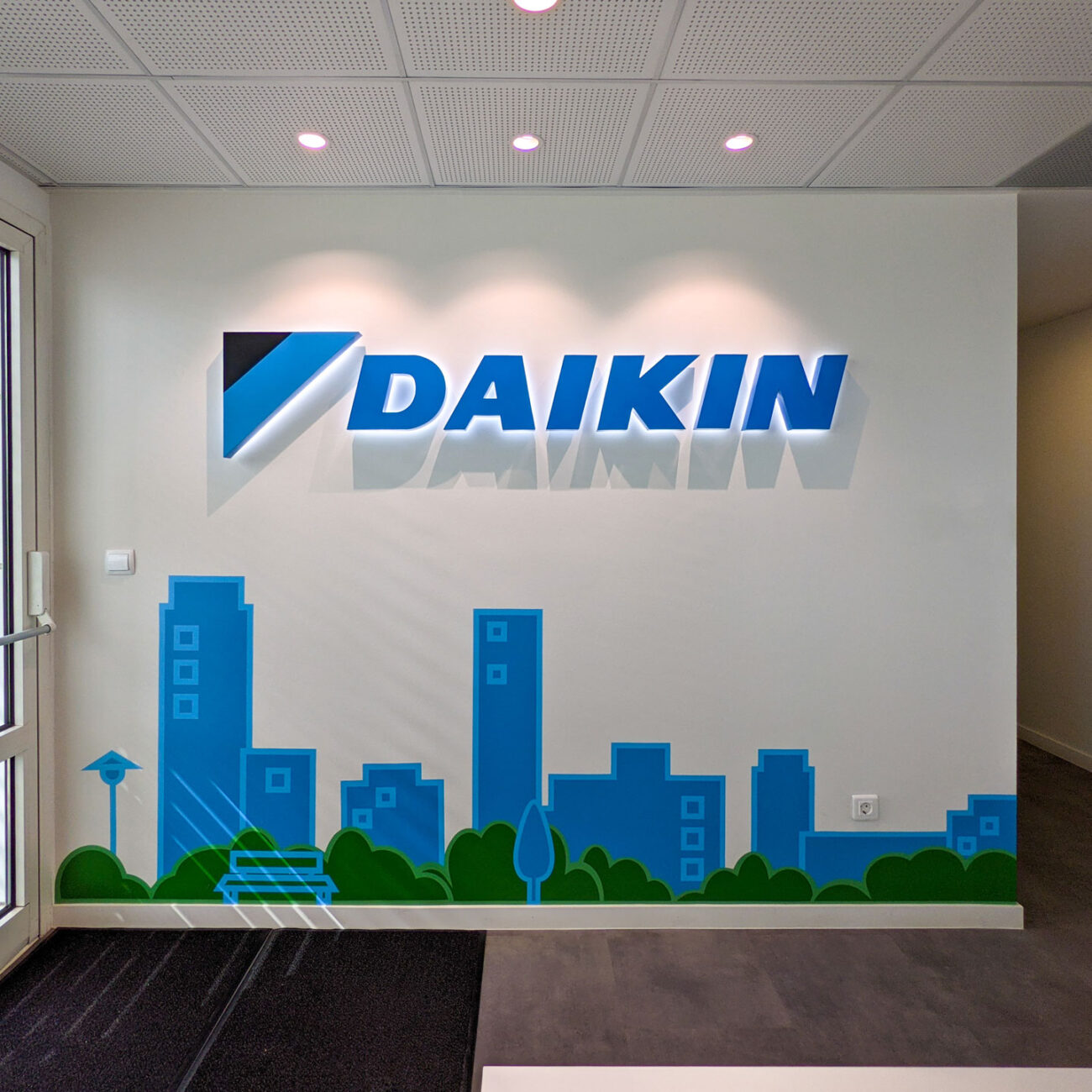 Daikin Hellas workplace project by STIRIXIS Group showing reception area with Daikin logo and blue cityscape brand wall graphic