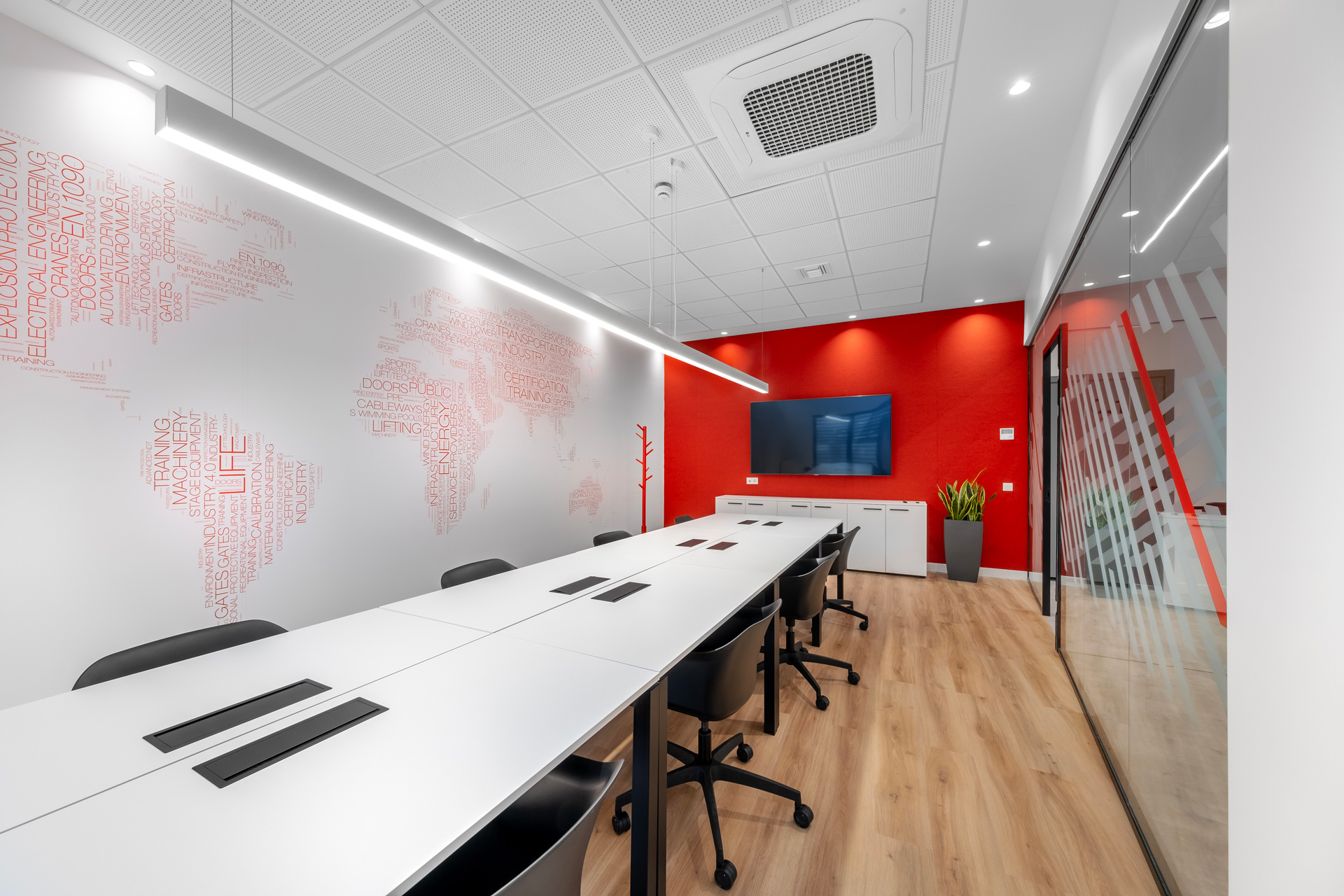 TUV Austria Hellas workplace project by STIRIXIS Group showing Thessaloniki meeting room with red accent wall and long white conference table