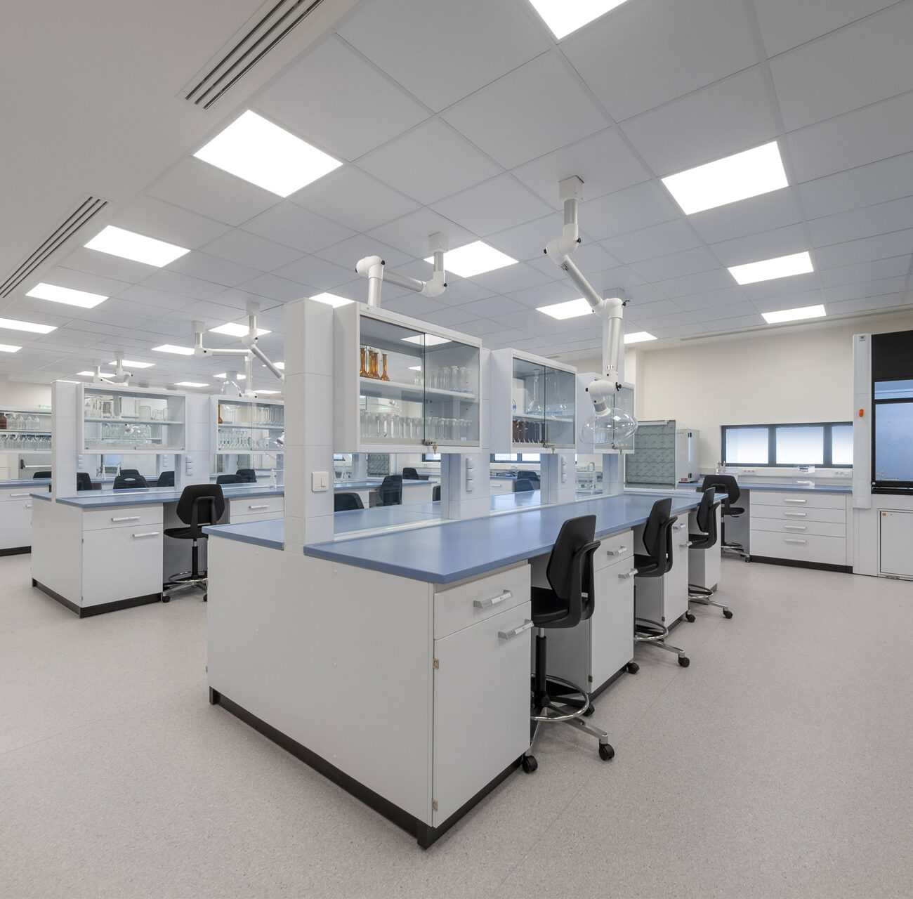 RAFARM R&D building workplace project by STIRIXIS Group showing laboratory with workbenches, integrated screen and clinical white interior