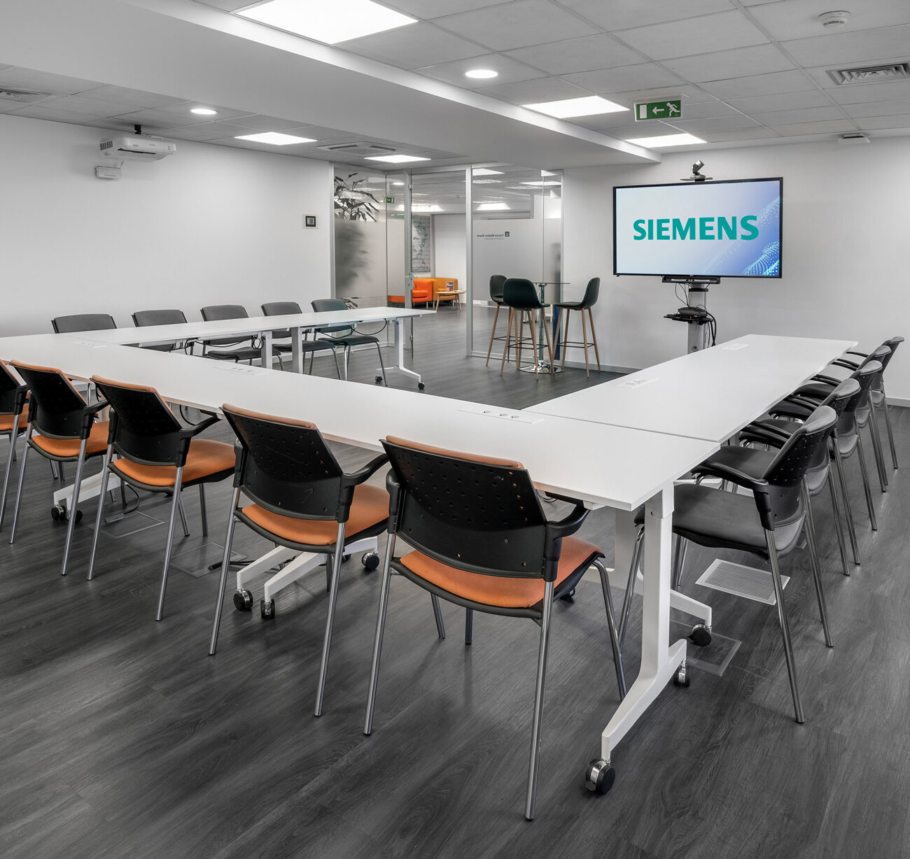 Siemens hybrid office workplace project by STIRIXIS Group showing large meeting room with presentation screen and modular table configuration
