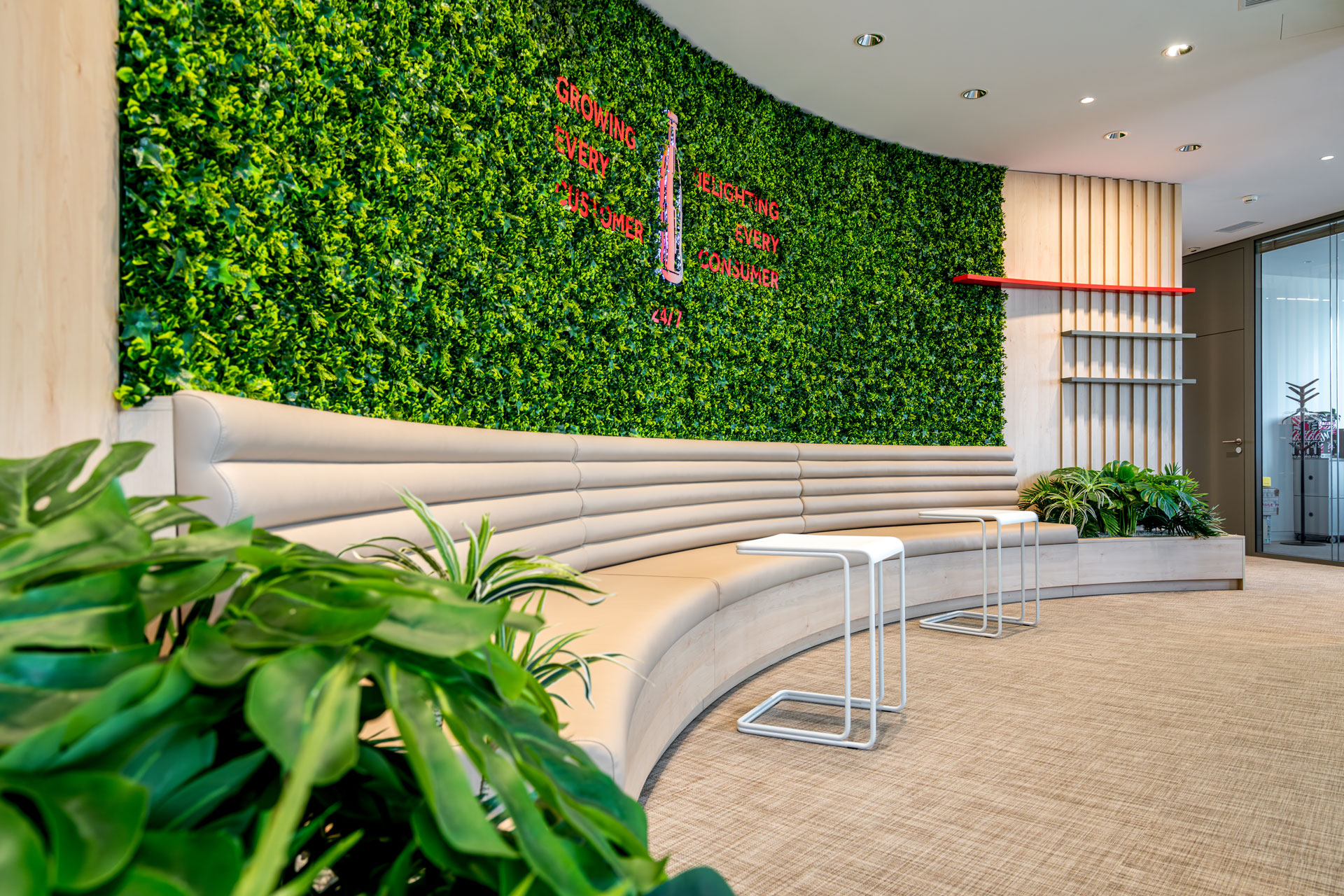Coca-Cola HBC headquarters workplace project by STIRIXIS Group showing reception area with large living green wall and curved white welcome desk