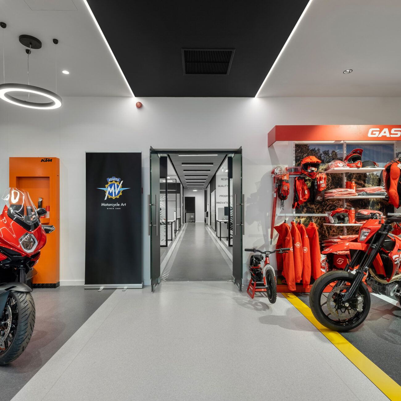 Petros Petropoulos showroom retail project by STIRIXIS Group showing entrance corridor with KTM motorcycles and orange brand accents