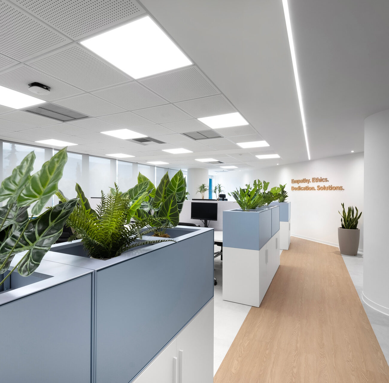 Intrum hybrid office workplace project by STIRIXIS Group showing open office corridor with biophilic planting and flexible workstation zones