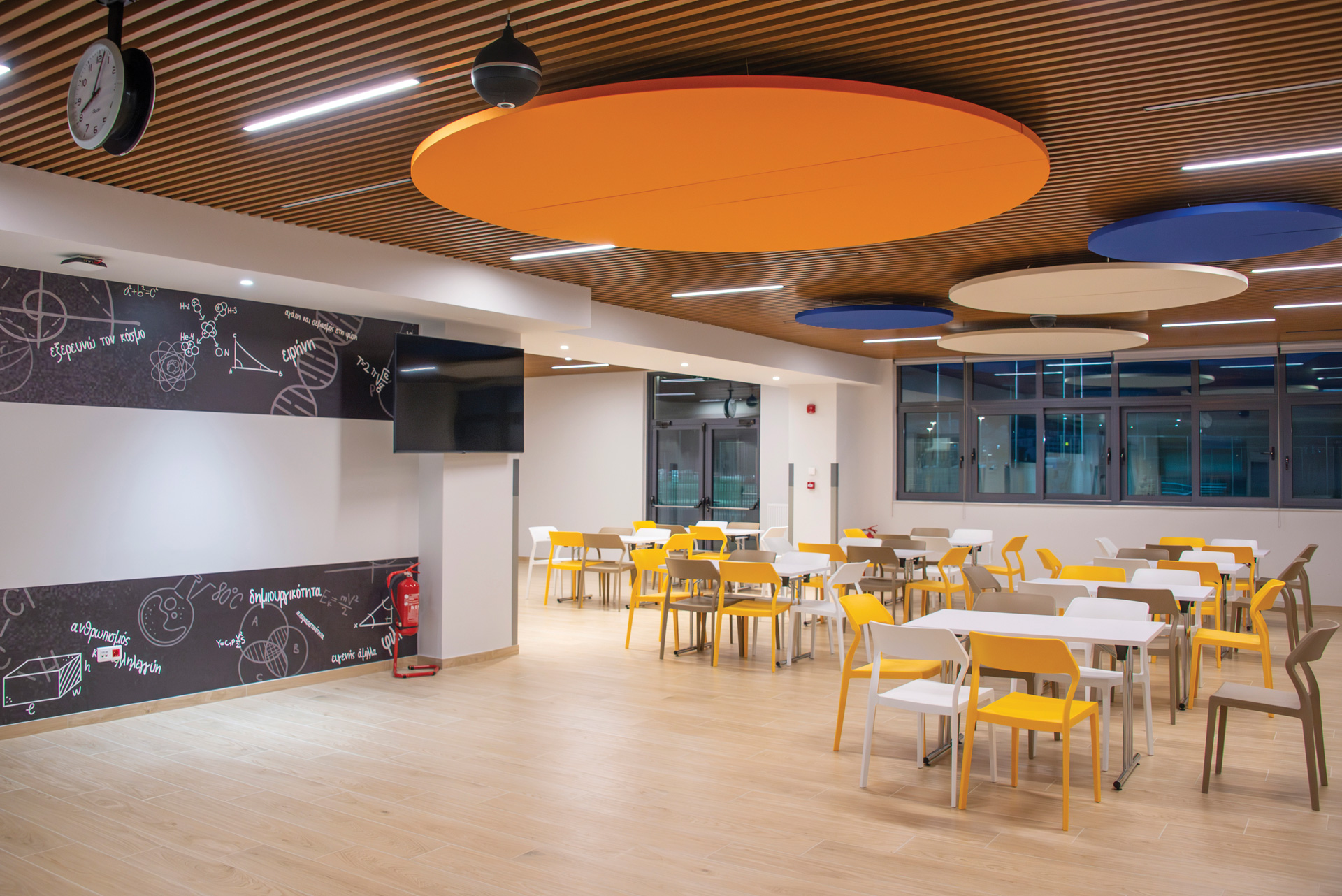 Saint Paul Delasalle school education project by STIRIXIS Group showing cafeteria with yellow chairs, circular ceiling feature and open dining layout