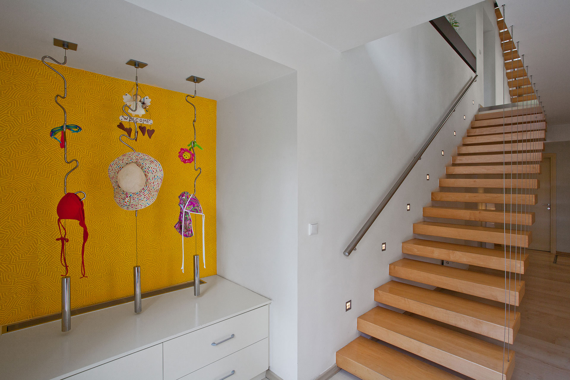 The Open House residential project by STIRIXIS Group showing staircase with bold yellow feature wall and contemporary art display