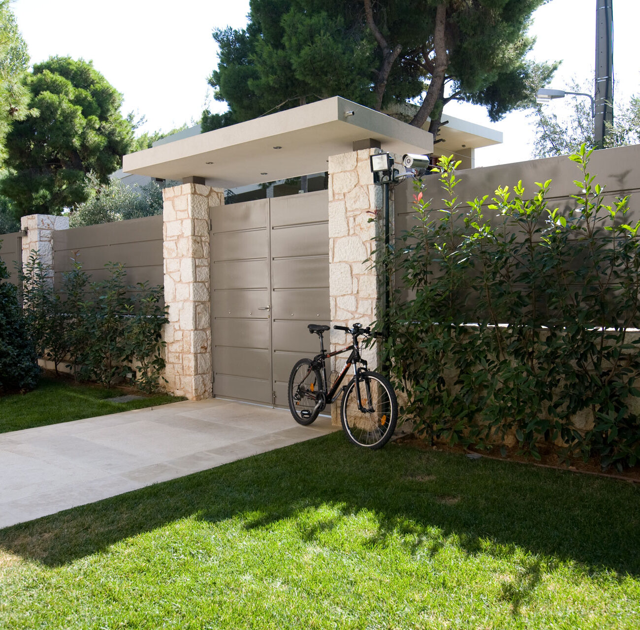 Projection House residential project by STIRIXIS Group showing exterior garage and driveway with landscaped garden and bicycle storage