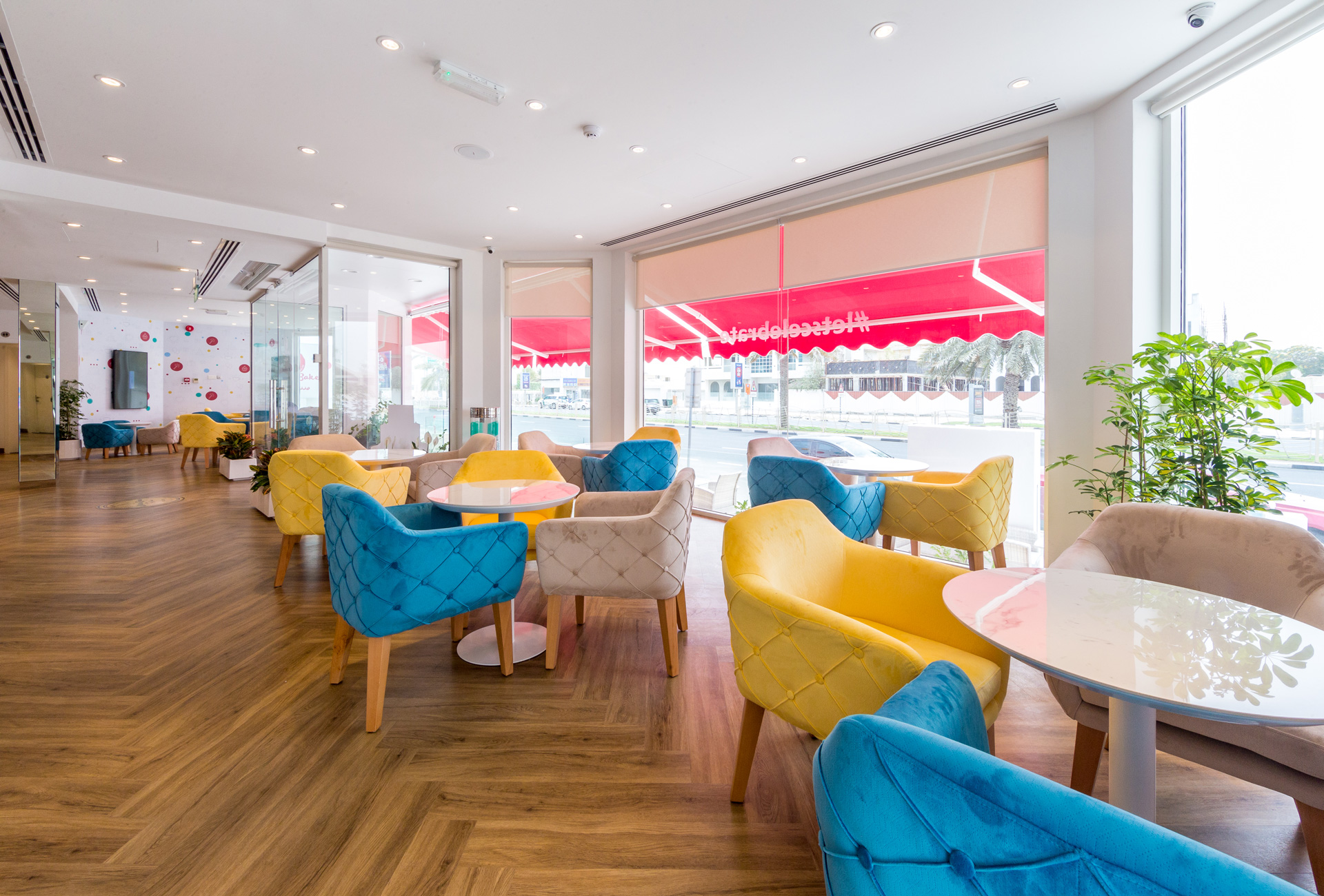 Mister Baker retail project by STIRIXIS Group showing cafe seating area with teal and yellow chairs and light-filled interior