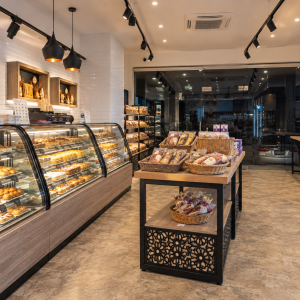 Interior of the MOB bakery project by STIRIXIS Group, with pastry displays, retail shelving and a central product island.