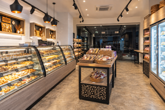 Interior of the MOB bakery project by STIRIXIS Group, with pastry displays, retail shelving and a central product island.